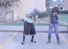 a man and a woman are dancing in a parking lot in front of a building .