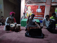 a man playing a musical instrument in front of a sign that says ' kannada '