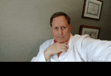 a man in a white coat is sitting in front of framed pictures