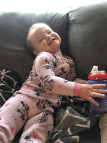 a little girl wearing a minnie mouse pajamas is laying on a couch