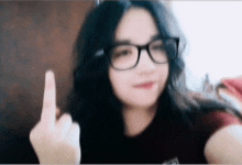 a woman wearing glasses is making a middle finger gesture .