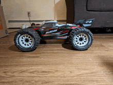 a traxxas sledge is sitting on a wooden floor next to a couch