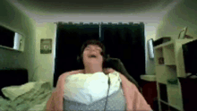 a woman wearing headphones is sitting in a bedroom with her mouth open