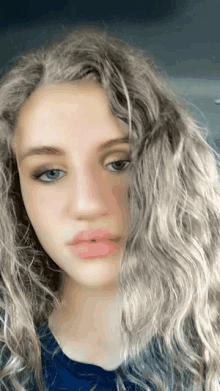 a young woman with long curly hair and blue eyes