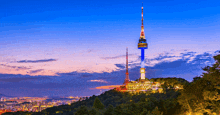 a tower on top of a hill with a city behind it