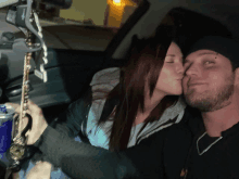 a man and a woman kissing in a car with a red bull in the background