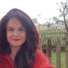 a woman wearing a red hooded jacket smiles for the camera