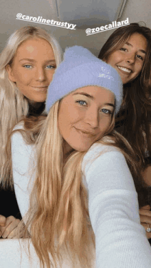 three women are posing for a picture and one of them is wearing a blue beanie