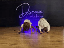 two girls are doing a handstand in front of a sign that says dream catchers dance company