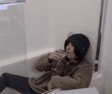 a person is sitting in a bathtub holding a glass of wine