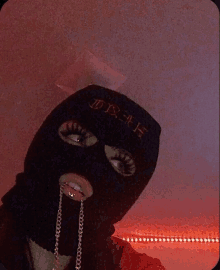 a person wearing a ski mask with a chain hanging out of their mouth