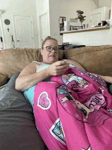 a woman sits on a couch with a lol surprise blanket