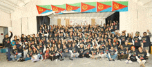 a large group of people are posing for a photo in front of a stage with flags hanging on it