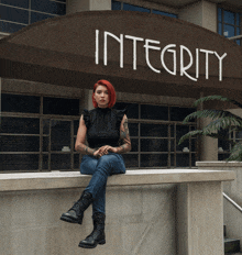 a woman sits on a ledge in front of a sign that says integrity