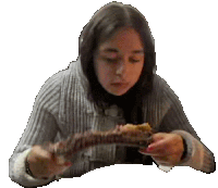 a young woman is sitting at a table eating a piece of meat .