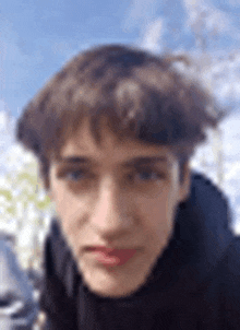 a close up of a young man 's face against a blue sky with clouds .