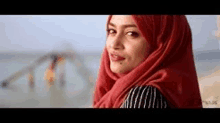 a woman wearing a red scarf is standing on a beach .