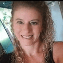 a close up of a woman 's face with curly hair smiling .