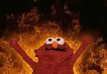 elmo from sesame street is standing in the middle of a fire .