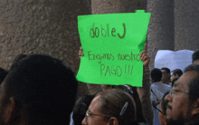 a woman holds up a sign that says doblej enigma nuestro pago !!!