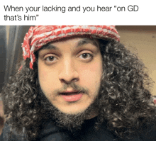 a man with curly hair and a beard is wearing a red and white scarf around his head