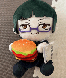 a stuffed doll with glasses is holding a hamburger and a tag that says taito