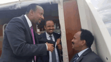 three men in suits and ties are standing next to each other and talking