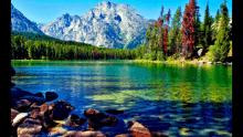 a lake surrounded by trees and mountains with a mountain in the background