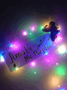 a sign that says " amats ms. purple " is surrounded by colorful lights and a butterfly