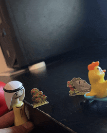 a toy duck sits on a table next to a man and a tree