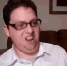 a man wearing glasses is making a funny face in a living room .