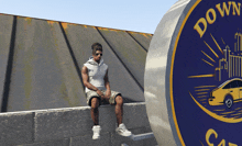 a man sits on a ledge in front of a sign that says down