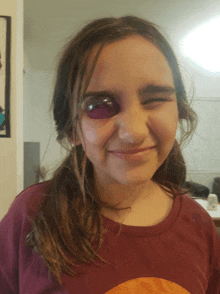 a young girl with a purple eye is smiling and winking at the camera