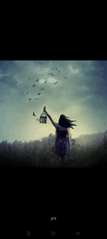 a woman is holding a cage with birds flying out of it and the time is 3/4