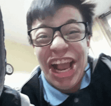 a young man wearing glasses and a blue shirt makes a funny face