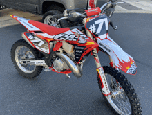 a red and white dirt bike has the number 7 on the front