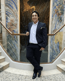 a man in a suit stands in front of stairs