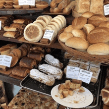 a variety of breads and pastries are displayed on a bakery shelf