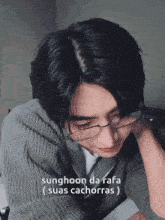 a young man wearing glasses and a grey sweater with the words sunghoon da rafa suas cachorras on the bottom