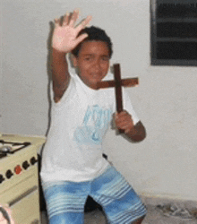 a young boy is holding a wooden cross and waving