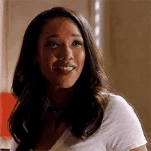 a woman is smiling and looking at the camera while wearing a white t-shirt .