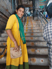 a woman in a yellow dress stands on a set of steps