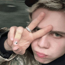 a young man with a ring on his finger is giving a peace sign