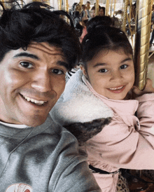 a man and a little girl are posing for a picture while riding a merry go round