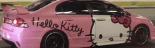 a pink hello kitty car is driving down the street .