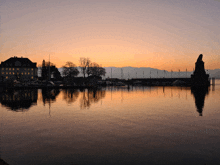 a sunset over a body of water with a building in the distance