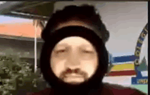 a man with a beard is wearing a mask on his face while talking on a video call .