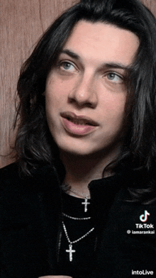 a young man wearing a black jacket and a cross necklace