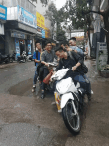 a group of young men are riding scooters down a wet street in front of a building that says cat toc man