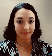 a woman wearing a necklace and a black and white shirt smiles for the camera